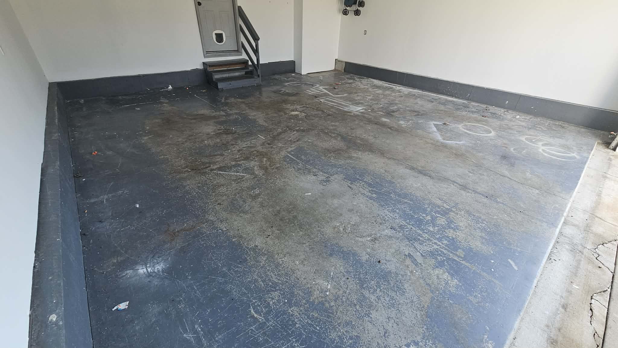 Stained and cracked bare concrete floor in a Liberty MO two-car garage before coating