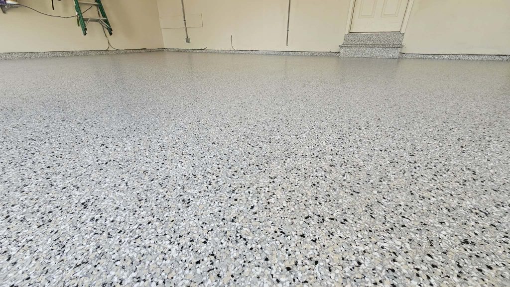 Finished 3 car garage epoxy flooring in North Kansas City MO with gray, black and white flake and a coved wall base