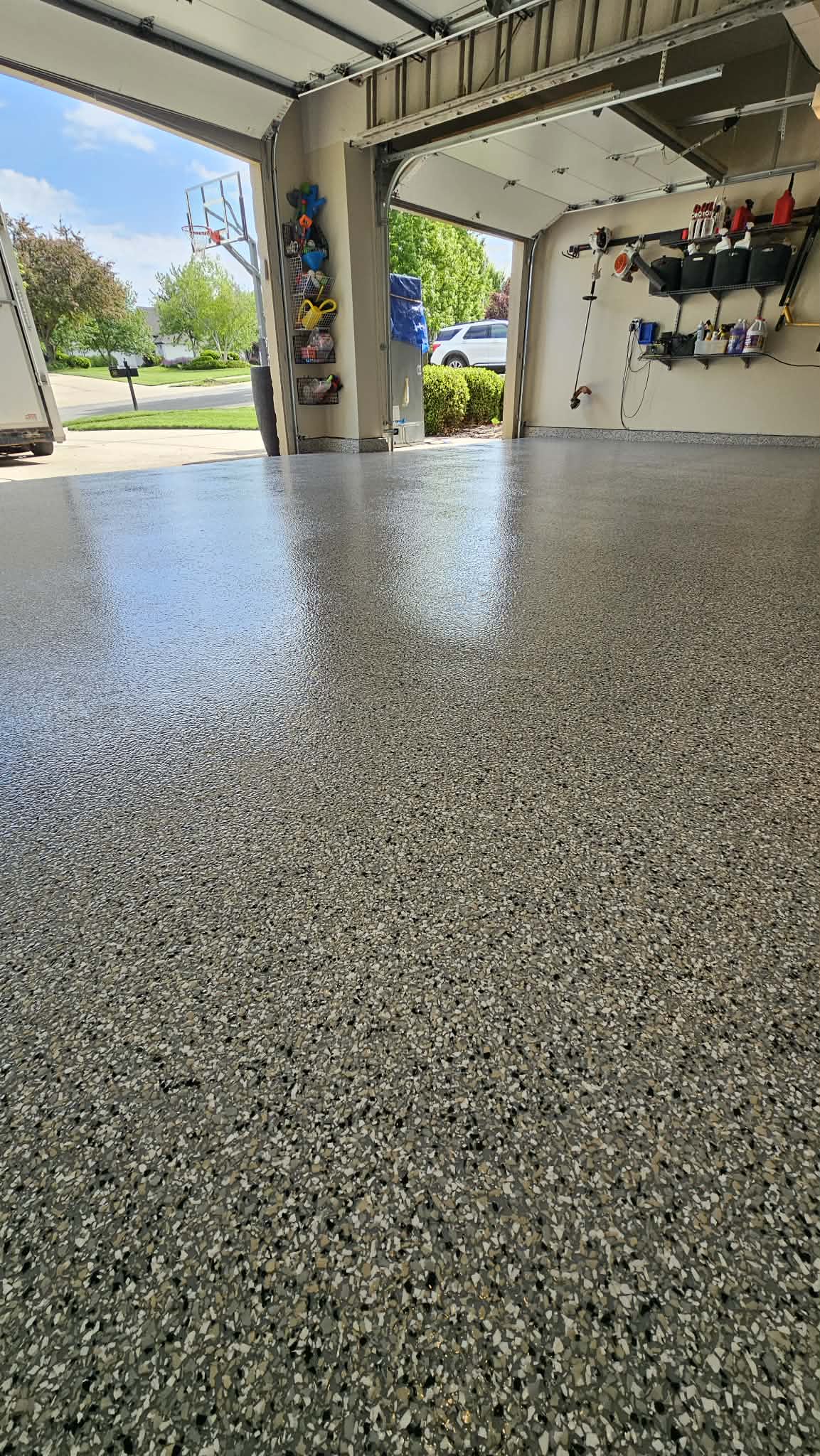 Three car garage in North Kansas City with new flake epoxy floor running to the garage door line, doors open to the driveway