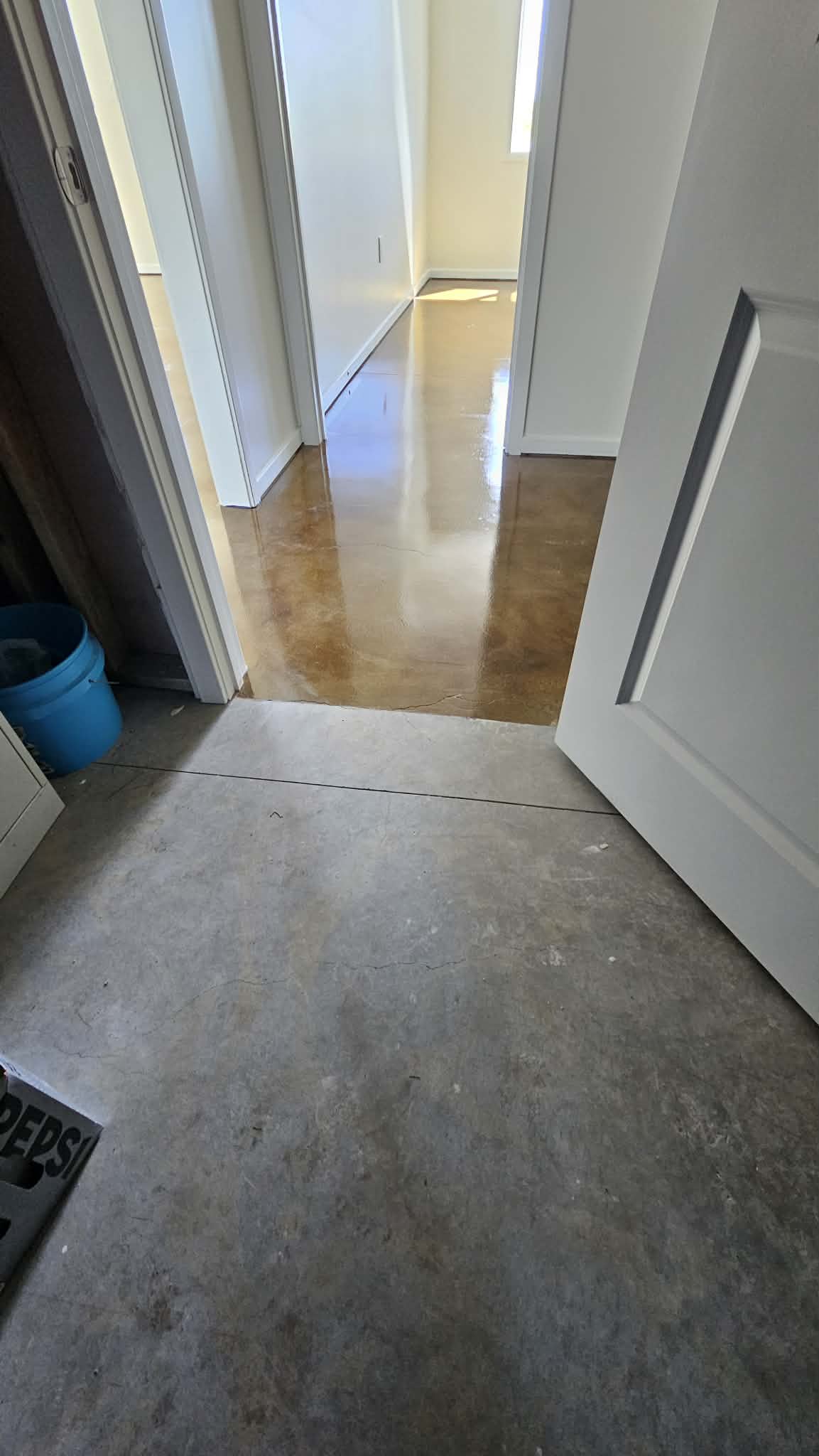 Hallway in a Peculiar MO basement showing stained concrete on one side of the doorway and bare gray slab on the other