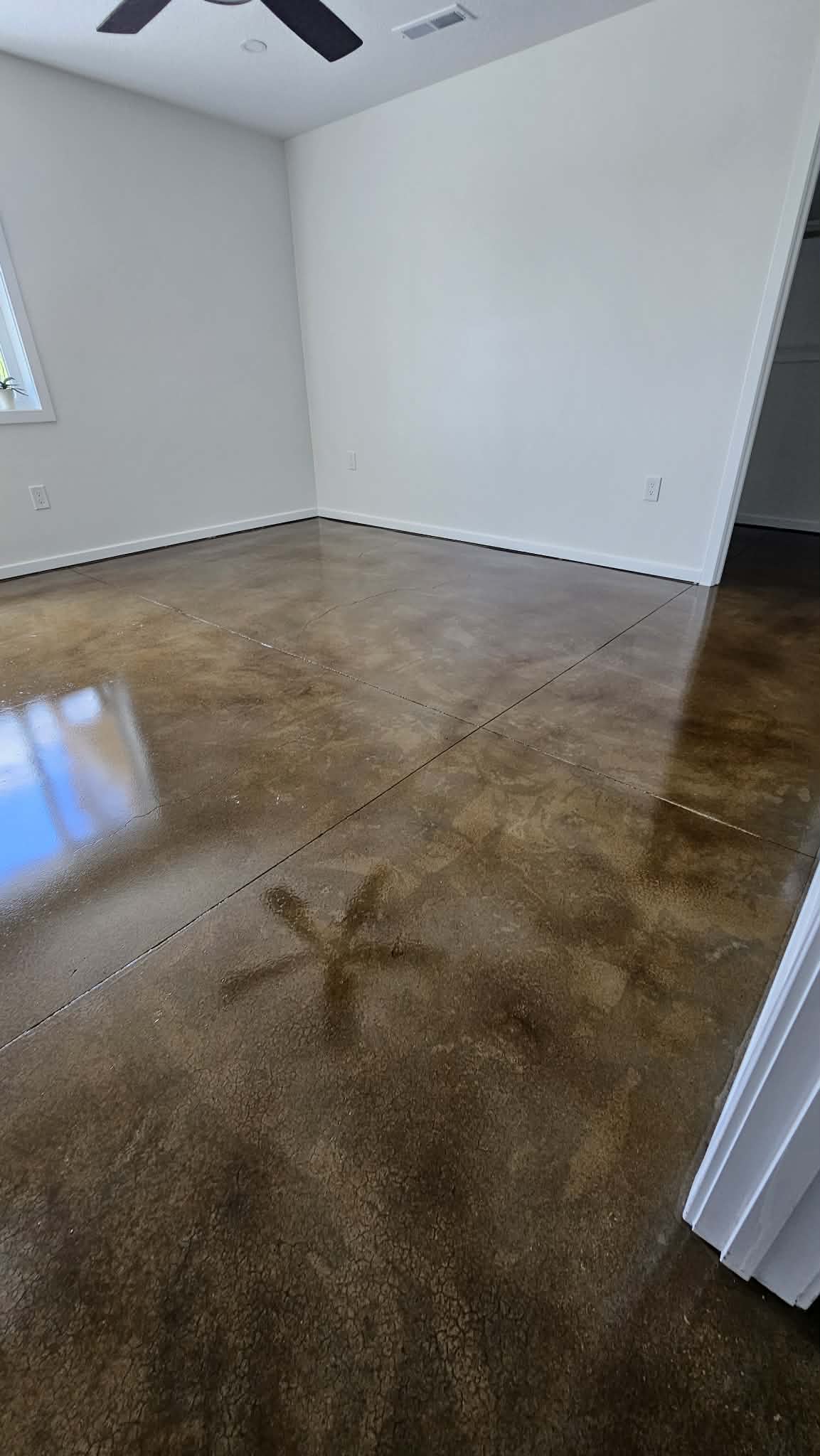 Stained concrete basement floor in Peculiar MO showing saw-cut control joints forming a large square grid