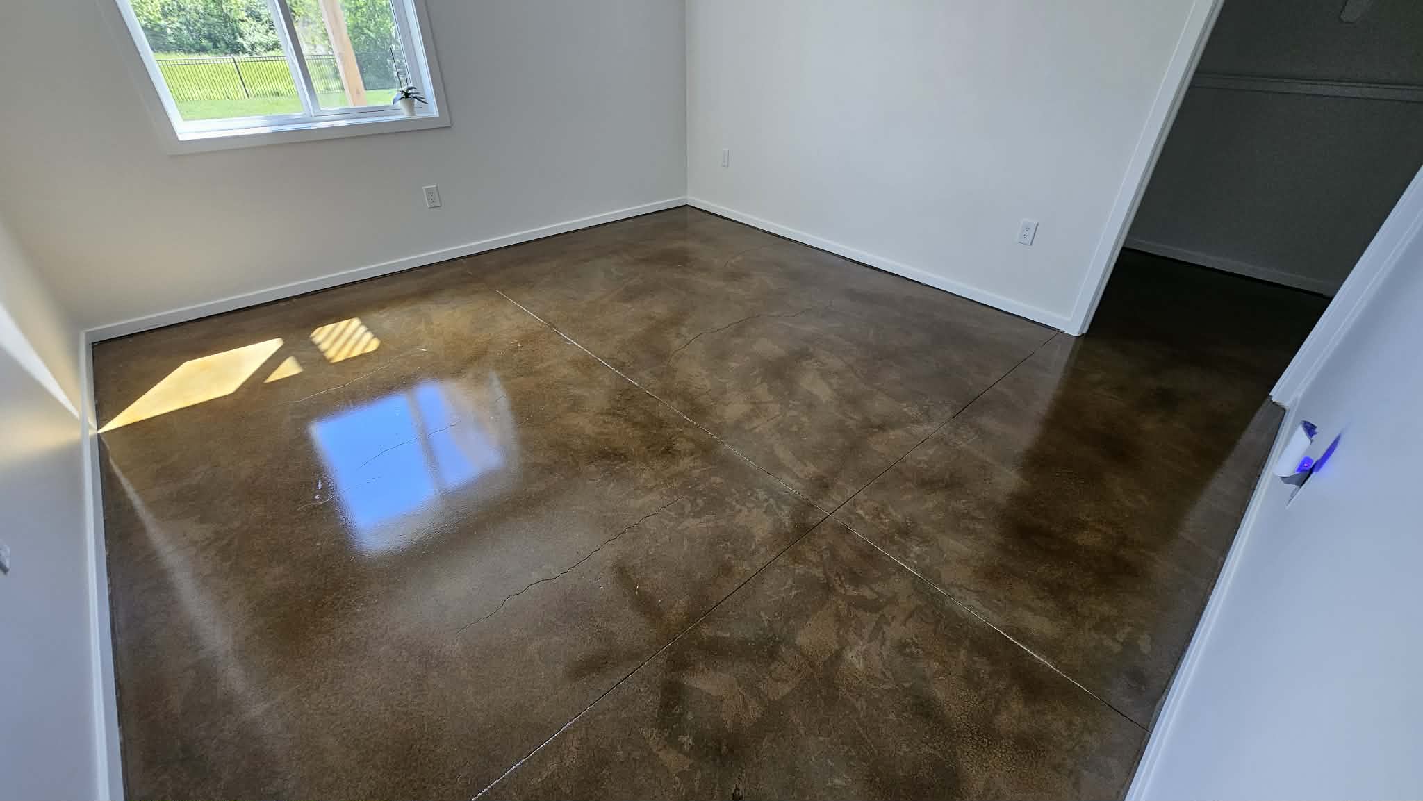 Basement bedroom in Peculiar MO with warm brown stained concrete floor, window and closet opening