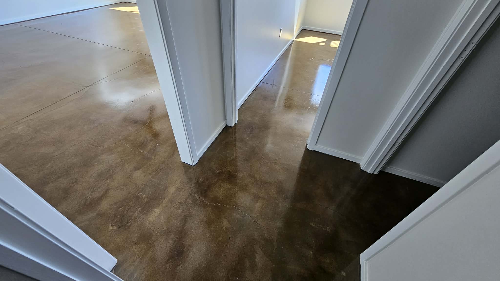Hallway with stained and sealed concrete running continuously between rooms in a Peculiar MO basement