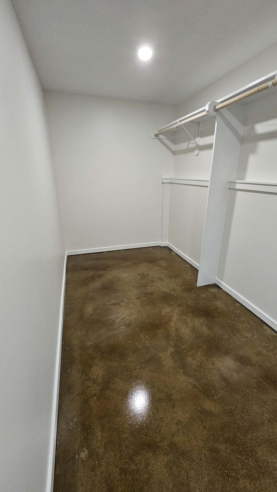 Walk-in closet in a Peculiar MO basement with stained concrete floor and wire shelving