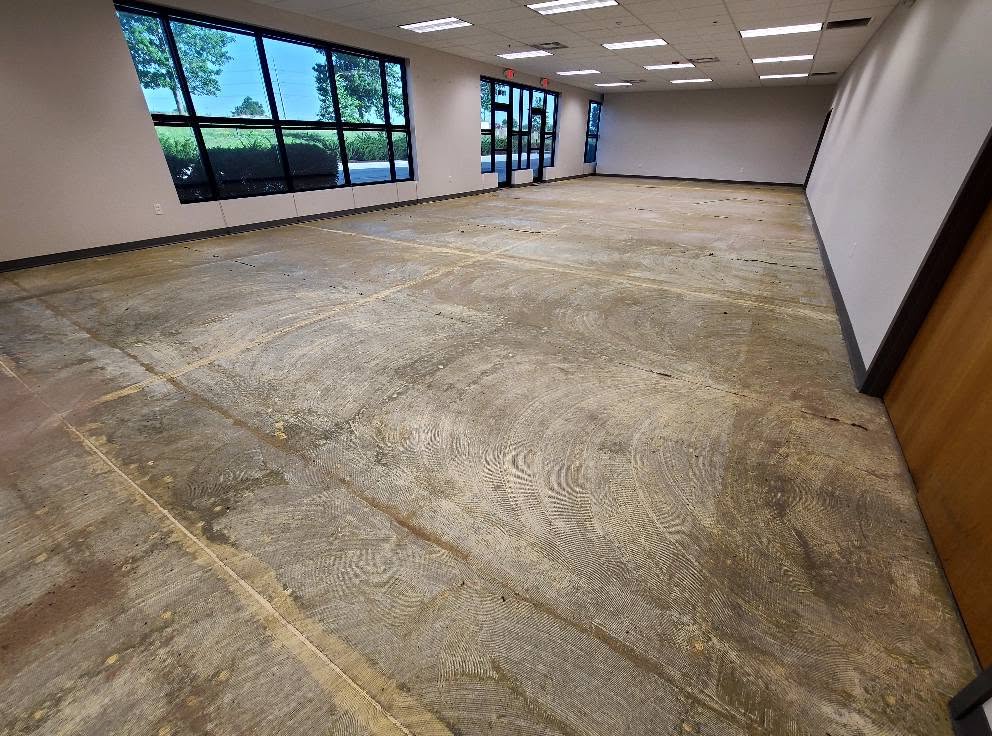 Bare concrete slab with old flooring adhesive and trowel swirl shadows before coating at Butler Supply Lenexa KS