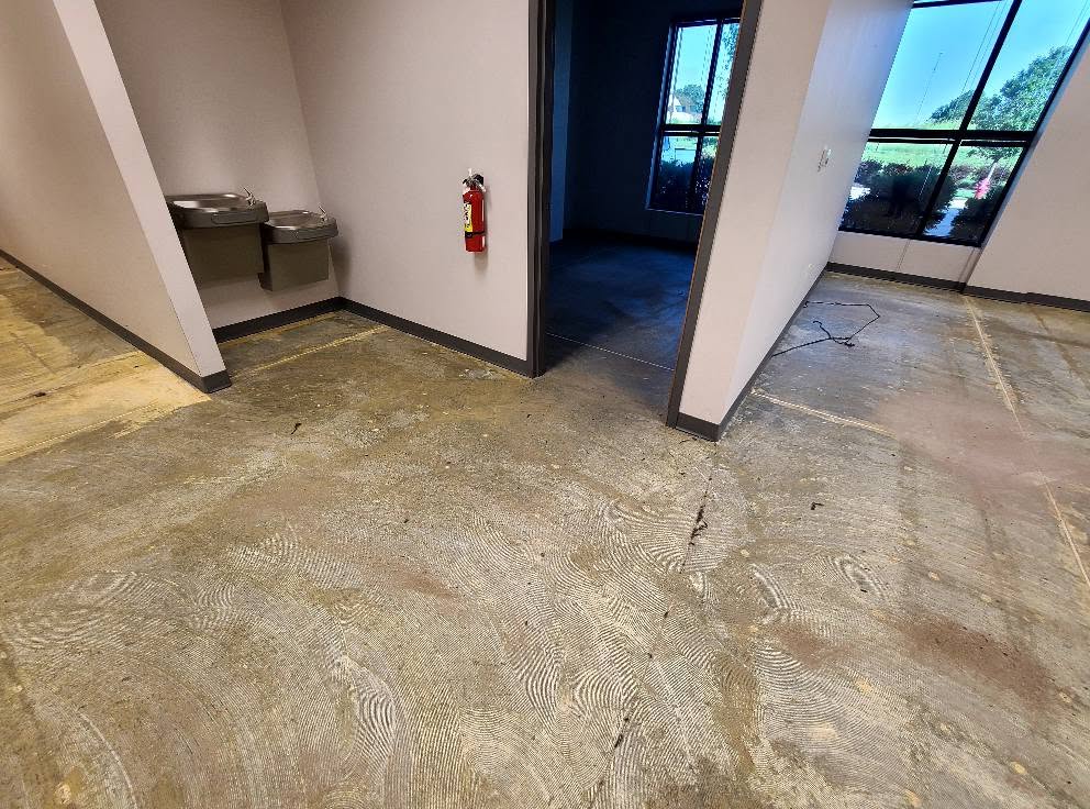 Adhesive residue on a commercial concrete slab near the drinking fountains before epoxy coating in Lenexa KS