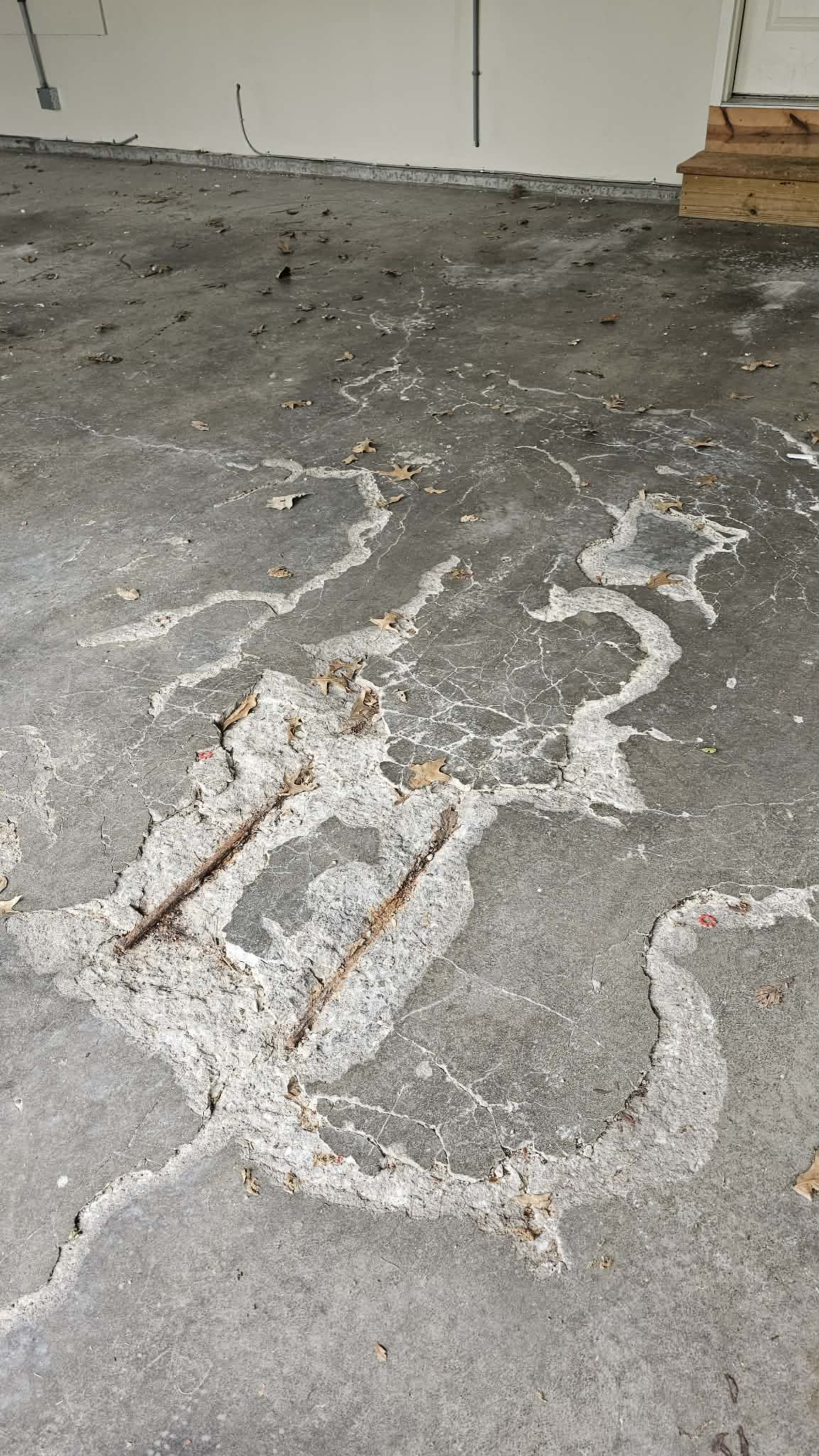Spalled and delaminated concrete garage floor before epoxy in North Kansas City with map cracking and exposed rusted wire mesh