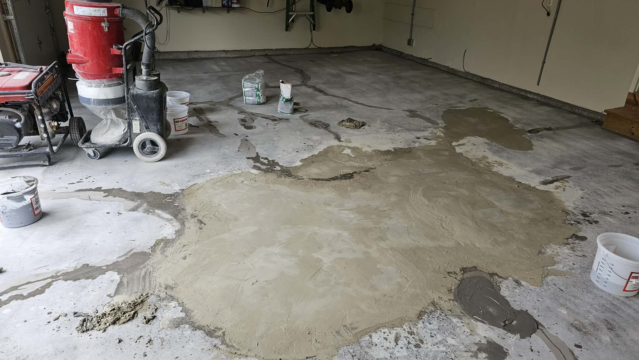 Concrete repair in progress on a Kansas City garage floor with diamond grinder, HEPA dust collection and fresh polymer-modified patching compound