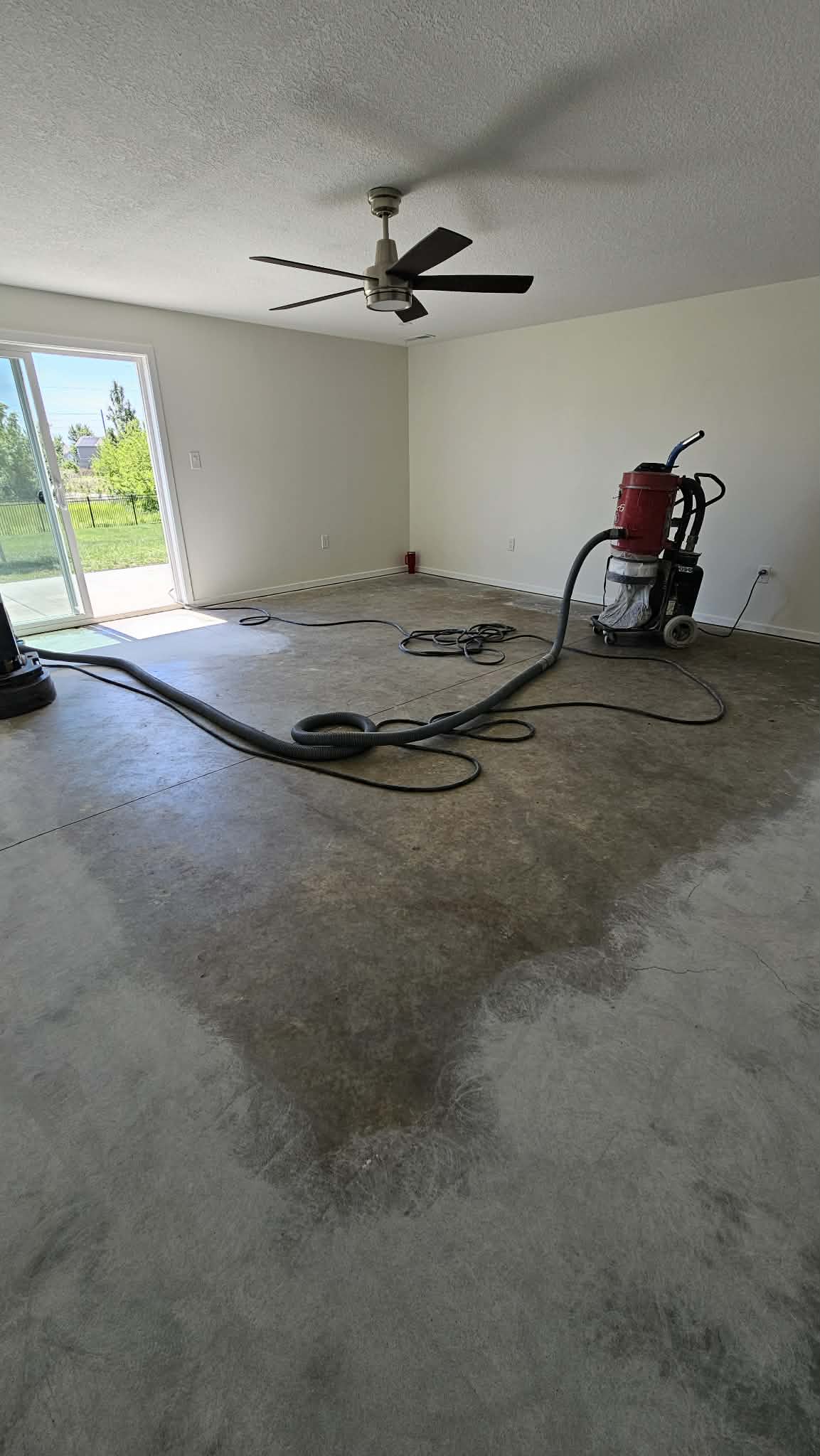 Bare basement slab in Peculiar MO with planetary grinder and HEPA vacuum before staining